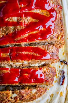 sliced meatloaf covered in ketchup on top of a baking sheet with sauce