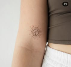 a woman's arm with a small sun tattoo on the back of her left arm