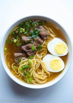 a bowl filled with noodles, meat and eggs on top of it's side