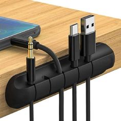 an iphone charging on a wooden table with multiple cables