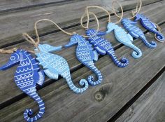 three blue seahorses are hanging on a wooden bench with twine strings attached to them