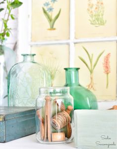 there are many vases and other items on the table with pictures behind them in glass jars