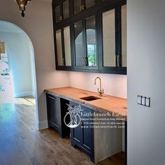 a kitchen with black cabinets and wooden floors