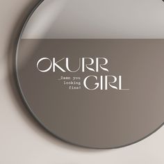 a round mirror with the words okurr girl in white on it's side