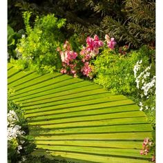 a wooden bench sitting in the middle of a lush green park filled with lots of flowers