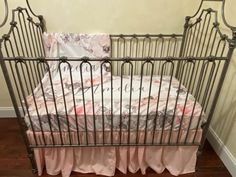 a baby crib with pink and white sheets on it