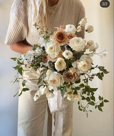 a woman holding a bouquet of white and pink flowers in her hands, with long hair