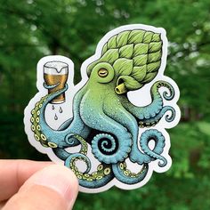 a hand holding up a sticker with an octopus and beer in the glass on it