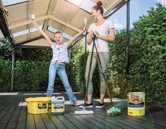 a woman and child are cleaning the deck with mop's in front of them