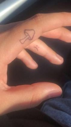 a person's hand with a small bow tattoo on their left thumb and finger