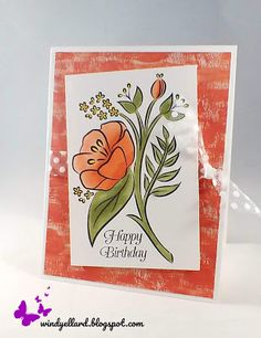 an orange and white birthday card with some flowers on it's front, sitting on a table