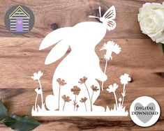 the silhouette of a rabbit is shown on a wooden surface with flowers and greenery