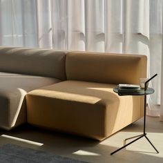 a beige couch sitting in front of a window next to a table with a cup on it