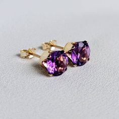 Striking deep shades of purple when seen from different angles. These earrings are available in your choice of a 14K gold-filled setting, 14k solid gold setting, or .925 solid silver setting. Both gold metals are tarnish resistant, water resistant, and hypoallergenic. These timeless stones are 6mm, making is roughly a half carat each. Whether you need a pair of earrings for everyday use or a special occasion, these classic studs won't disappoint. IMPORTANT: Both 14k solid gold and 14k gold-fille Purple Amethyst Earrings With Prong Setting, 14k Gold Purple Earrings With Prong Setting, Purple 14k Gold Earrings With Prong Setting, Purple Birthstone Earrings Fine Jewelry, Purple Birthstone Earrings For Formal Occasions, Purple Amethyst Birthstone Earrings, Formal Purple Birthstone Earrings, Classic Purple Gemstone Earrings, Classic Purple Jewelry With Matching Earrings