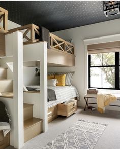 a bedroom with bunk beds and stairs leading up to the bed in front of a window