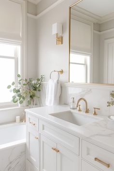 a white bathroom with marble counter tops and gold accents