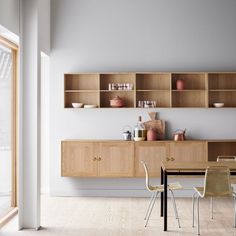 a dining room table with chairs and shelves above it