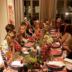 a group of people sitting around a table with plates and cups on it, all looking at each other