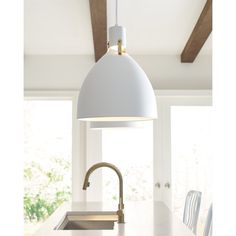 a white light hanging over a kitchen counter top next to a sink and stovetop