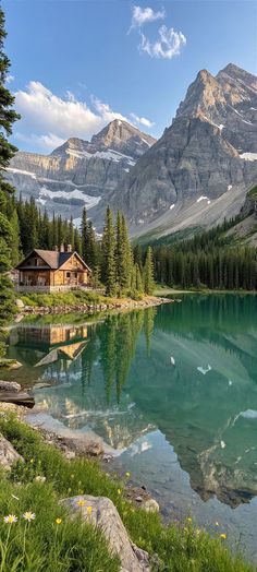 a lake surrounded by mountains and trees with a house on the shore next to it