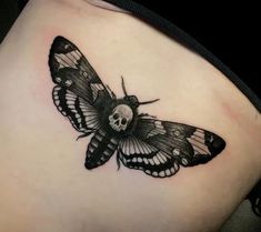 a black and white butterfly tattoo on the back of a woman's stomach,