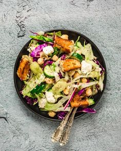 a salad with chicken, lettuce, and chickpea in a black bowl