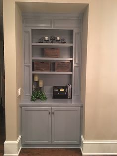 a gray bookcase with drawers and baskets on top in a room that has hard wood flooring