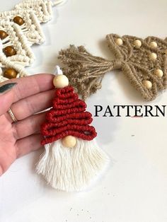 a hand holding a small christmas tree ornament on top of a white table