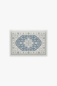 a blue and white rug with an intricate design on the bottom, in front of a white wall