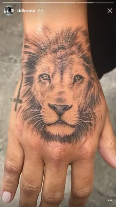 a hand with a lion tattoo on it and a cross in the middle is shown