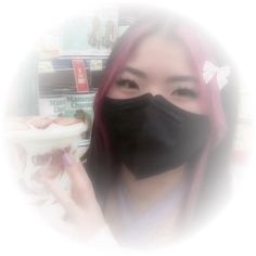 a woman with pink hair wearing a black face mask and holding a drink in front of her face