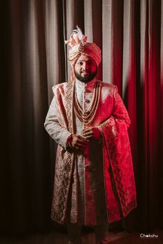 a man wearing a red and white outfit standing in front of curtains with his hands on his hips