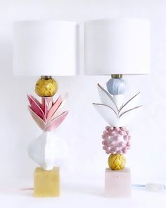 two lamps with flowers on them sitting next to each other in front of a white wall