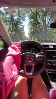 a person sitting in the driver's seat of a car with their feet on the steering wheel