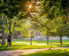 a man standing in the middle of a park with trees and people sitting on benches