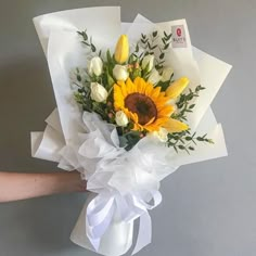 a bouquet of sunflowers and tulips wrapped in white paper