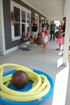 a group of people standing on the front porch playing with some balls and hoops