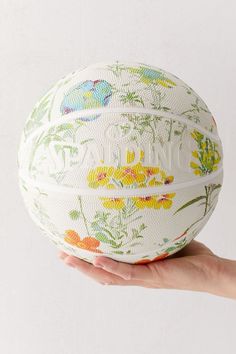 a hand holding a white and yellow floral print basketball