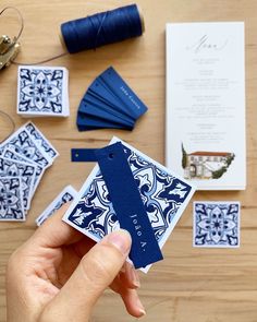 a person holding up a blue and white piece of paper next to some sewing supplies