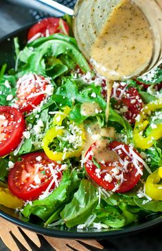 a salad with tomatoes, cheese and spinach in a black bowl on a table