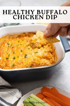 a hand dipping a tortilla chip into a casserole dish with carrots and celery