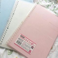 three notebooks sitting on top of a bed next to each other