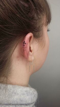 the back of a woman's ear with tattoos on it