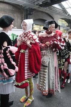 several women dressed in costumes and hats are walking down the street with their hands on their hips