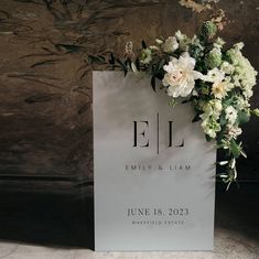 a sign with flowers on it sitting in front of a wall