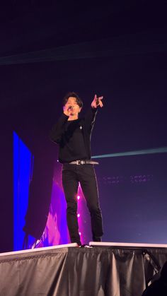 a man standing on top of a stage with his hands in the air