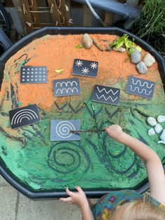 a child is playing with an art project made out of rocks and paper on a table