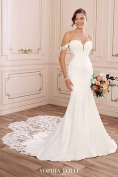 a woman in a white wedding dress standing on a wooden floor next to a flower bouquet