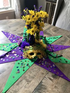 a table topped with purple and green paper cut outs, flowers and mardi gras