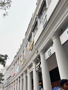 people walking on the sidewalk in front of a large building with columns and gold letters